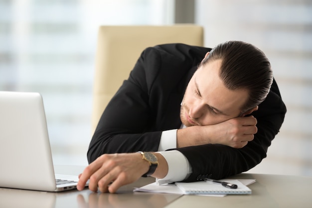 De zakenman neemt onderbreking en het sluimeren in bureau