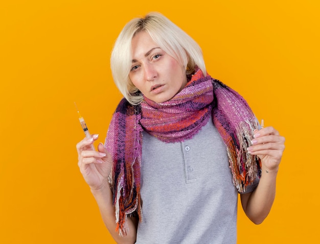 De zekere jonge blonde zieke Slavische vrouw die sjaal draagt houdt spuit