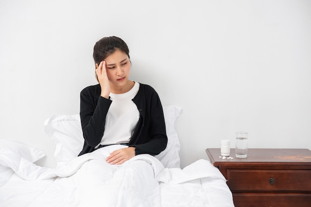 De zieke vrouw had hoofdpijn en de handen raakten haar hoofd op het bed.