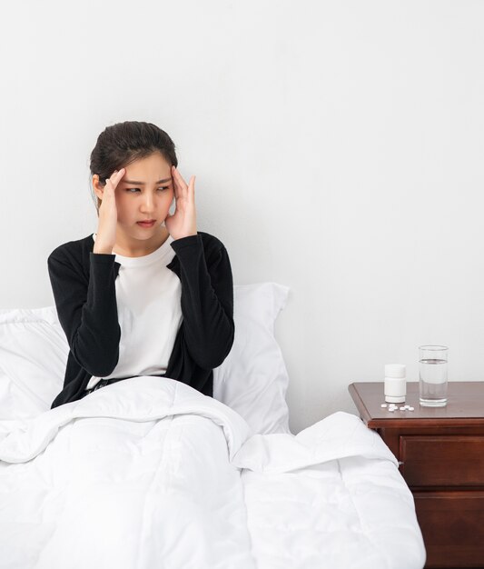 De zieke vrouw had hoofdpijn en de handen raakten haar hoofd op het bed.