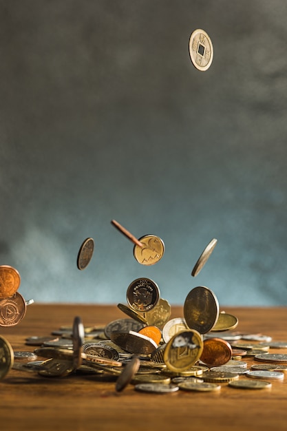 De zilveren en gouden munten en vallende munten op houten muur