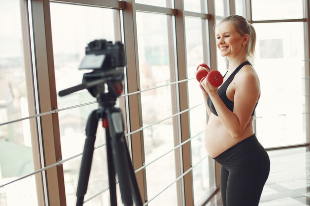 De zwangere vrouw speelt sporten met dambbels