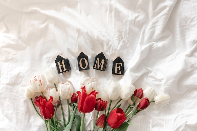 Gratis foto decoratief woordhuis en tulpen in een wit bed bovenaanzicht