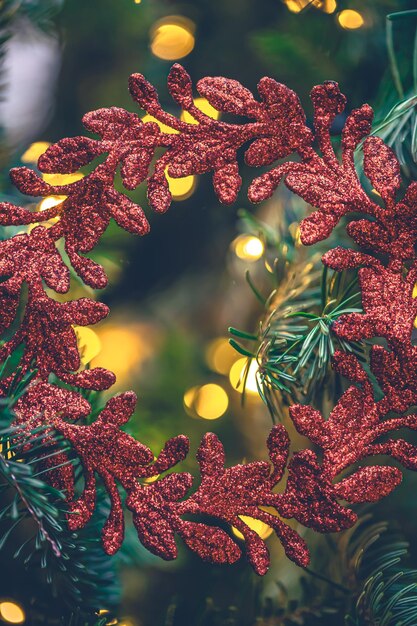 Decoratieve rode krans op een kerstboom met bokehlichten