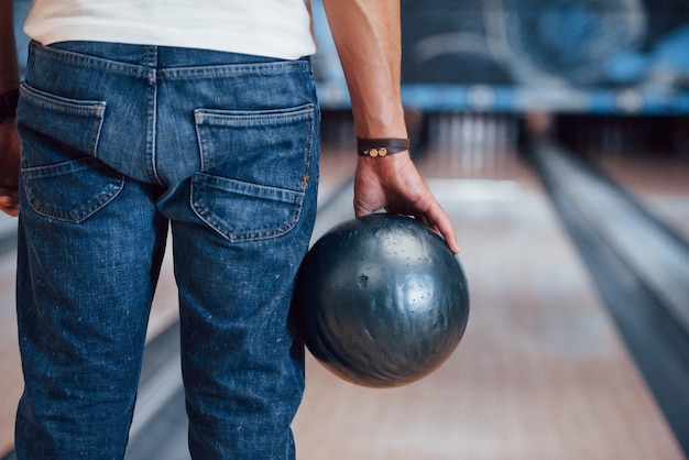 Deeltjes achteraanzicht van man in casual kleding bowlen in de club