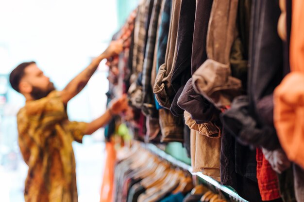 Defocussed man die overhemd van het spoor in de winkel kiest