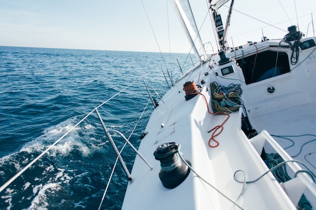 Dek van professionele zeilboot of racejacht tijdens wedstrijd op zonnige en winderige zomerdag, snel bewegend door golven en water, met spinnaker omhoog