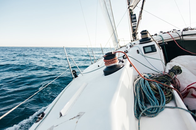 Dek van professionele zeilboot of racejacht tijdens wedstrijd op zonnige en winderige zomerdag, snel bewegend door golven en water, met spinnaker omhoog