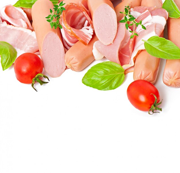 Delicaat vlees (worst en ham) versierd met basilicum en tomaten geïsoleerd