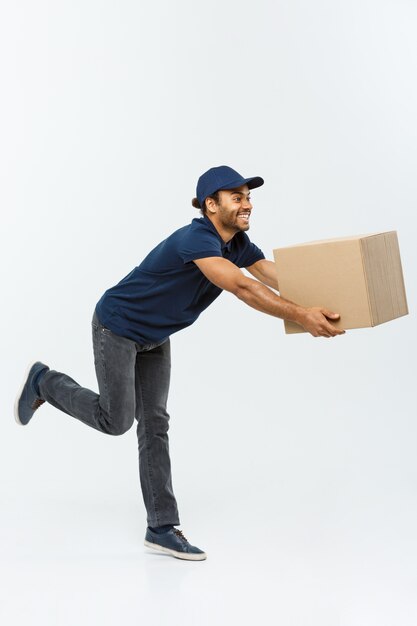 Delivery Concept - Knappe Afro-Amerikaanse leveringsman haast rijdt voor het leveren van een pakket voor de klant. Geïsoleerd op grijze studio achtergrond. Ruimte kopiëren.