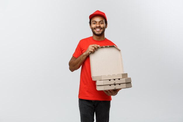 Delivery Concept - Portret van knappe Afro-Amerikaanse Pizza Delivery Man. Geïsoleerd op grijze studio achtergrond. Ruimte kopiëren.