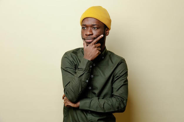 Denken greep kin jonge Afro-Amerikaanse man in hoed met groen shirt geïsoleerd op een witte achtergrond