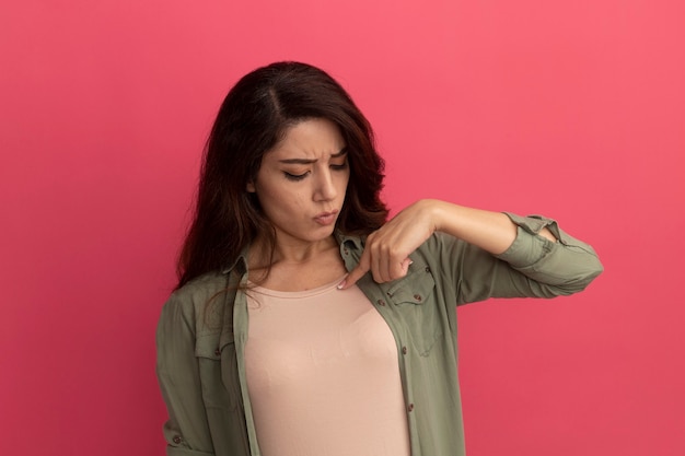 Denkende jong mooi meisje met olijfgroene t-shirt wijst naar zichzelf geïsoleerd op roze muur