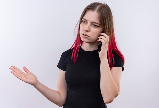 Denkende jong mooi meisje met zwarte t-shirt spreekt aan de telefoon hand opheffen op geïsoleerde witte muur met kopie ruimte