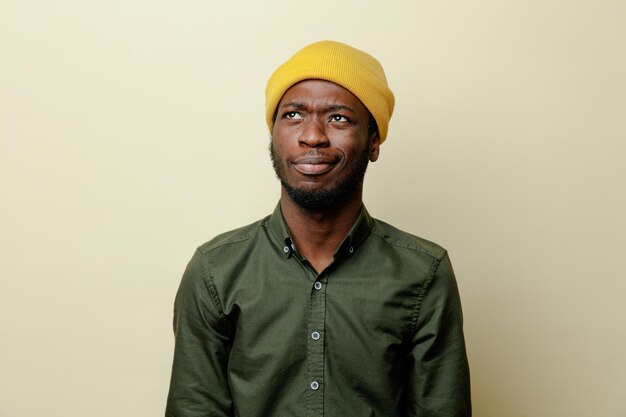 Denkende jonge Afro-Amerikaanse man in hoed met groen shirt geïsoleerd op witte achtergrond