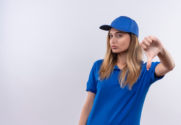 Gratis foto denkende jonge levering meisje draagt blauw uniform en cap haar duim naar beneden geïsoleerd op een witte muur met kopie ruimte