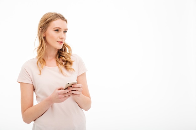 Denkende jonge vrouw die mobiele telefoon met behulp van.