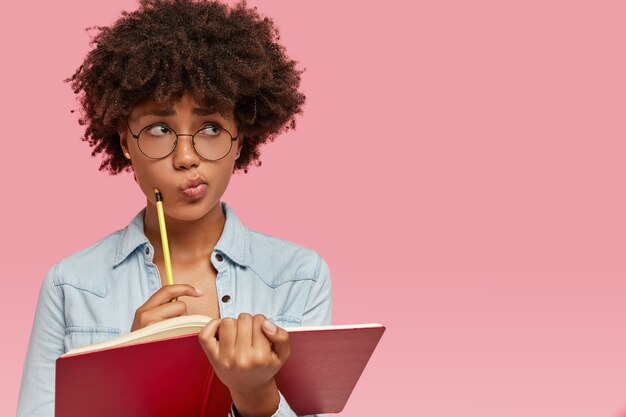 Denkende, verward donkere vrouw schuift haar lippen in verbijstering.