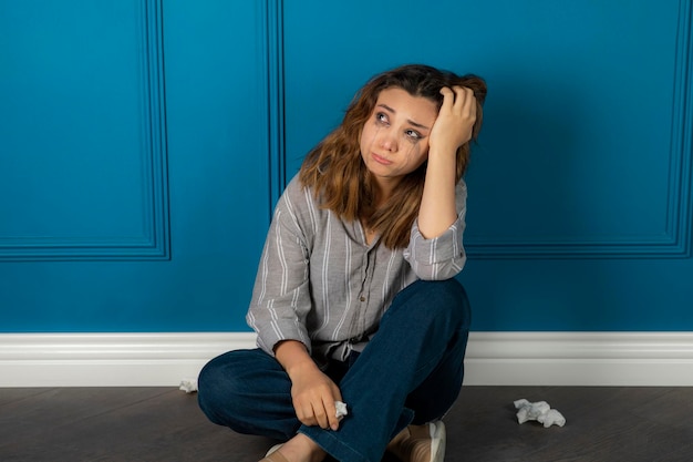 Depressieve jonge vrouw zittend op de vloer en denken. Hoge kwaliteit foto