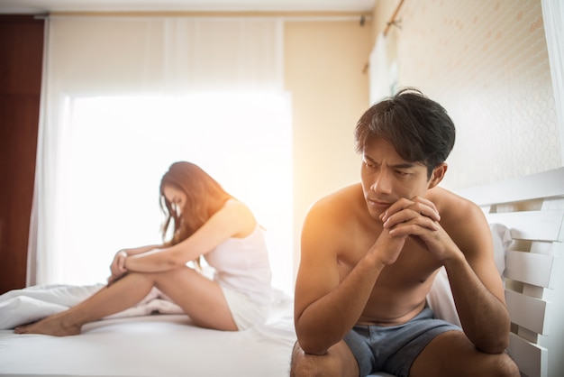 Depressieve man zittend op het bed in de slaapkamer hebben probleem met zijn vrouw