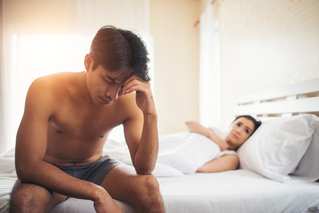 Depressieve man zittend op het bed in de slaapkamer hebben probleem met zijn vrouw