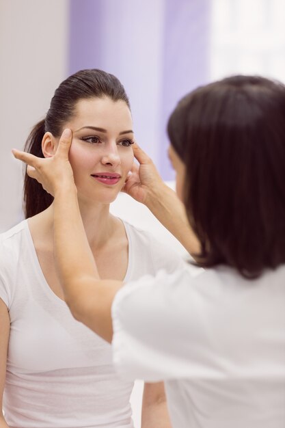 Dermatoloog die de huid van de vrouwelijke patiënt onderzoekt