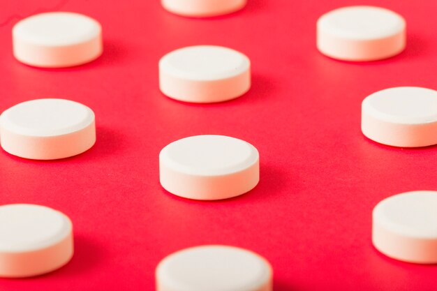 Detail van witte ronde pillen op rode achtergrond
