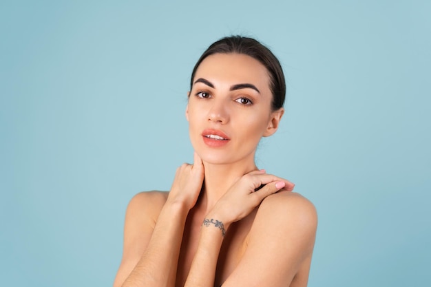 Dicht schoonheidsportret van een topless vrouw met perfecte huid en natuurlijke make-up, mollige naakte lippen, op een blauwe achtergrond