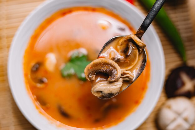 Dichte bovenaanzicht man houdt lepel champignonsoep met champignons