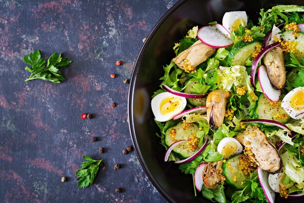 Dieetsalade met mosselen, kwarteleitjes, komkommers, radijs en sla. Gezond eten. Zeevruchten salade. Bovenaanzicht Plat leggen.