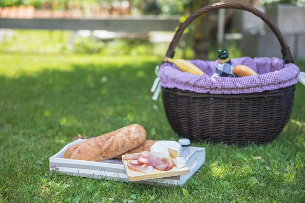 Dienblad met brood; spek; kaas en mand in park