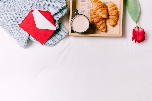 Dienblad met croissants en kop van melk op bed