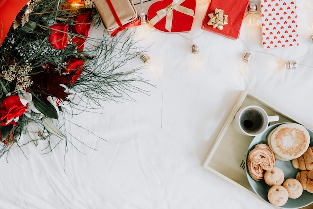 Dienblad met ontbijt dichtbij boeket en cadeaus