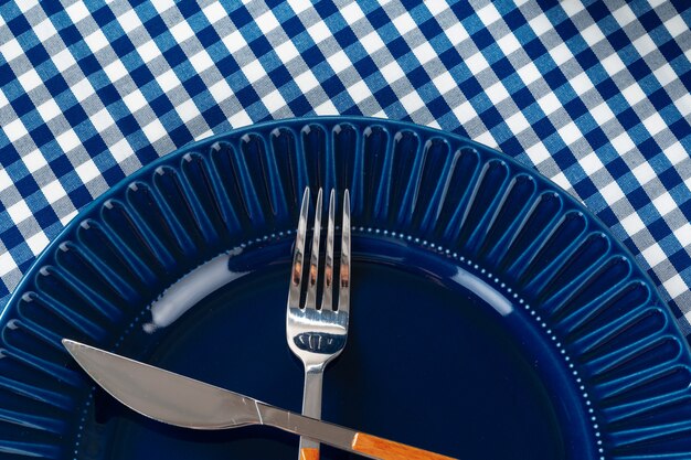 Diepblauwe keramische plaat met bestek op tafel