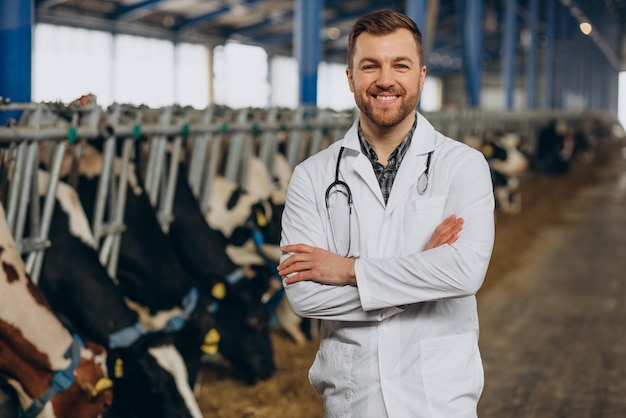 Dierenarts in laboratoriumjas staande bij koeienstal