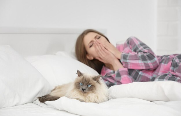 Dierlijk allergieconcept. mooie vrouw met kat in bed