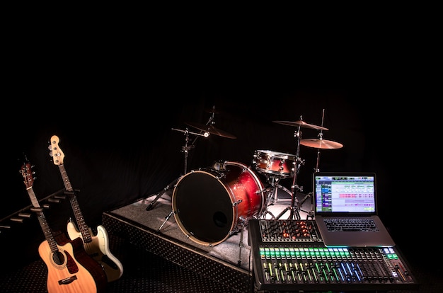 Digitale mixer in een opnamestudio, met een computer voor het opnemen van muziek. Op de achtergrond van een drumstel en muziekinstrumenten. Het concept van creativiteit en showbusiness.