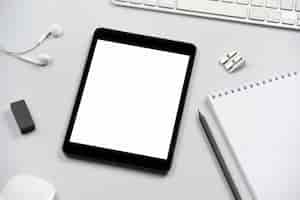 Gratis foto digitale tablet met lege witte scherm op het bureau