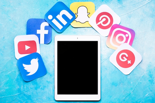 Digitale tablet rond kleurrijke sociale media pictogrammen op geschilderde blauwe achtergrond