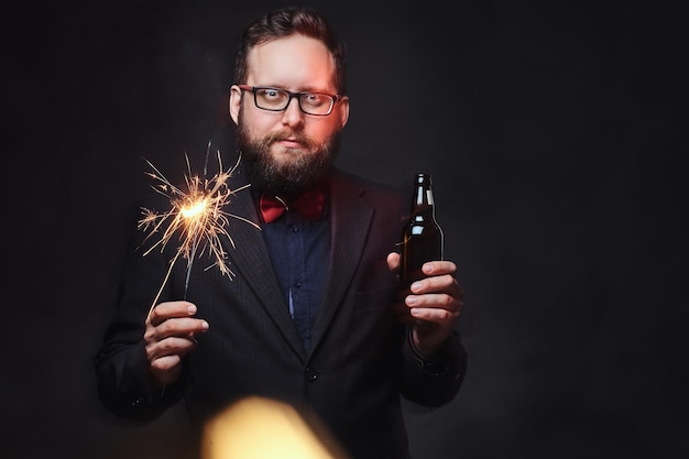 Dikke man in bril gekleed in een overhemd met vlinderdas drinkt ambachtelijk bier uit een fles.