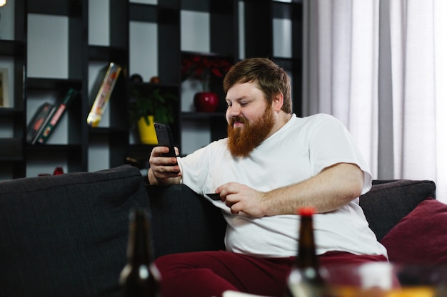 Dikke man typt het nummer van een creditcard in zijn telefoon op de bank