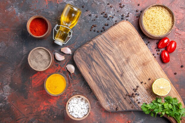 Diner achtergrond met ongekookte pasta snijplank citroen een bos groene tomaten verschillende kruiden op donkere tafel