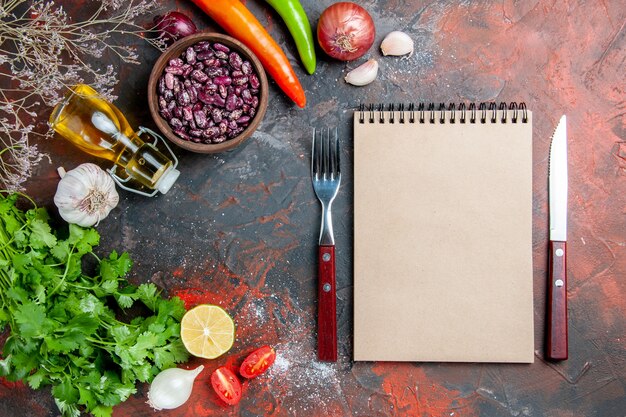 Diner voorbereiding met voedsel en bonen olie fles en een bos van groene citroentomaat en notebook op gemengde kleurentafel