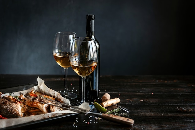 Dinerconcept met twee glazen witte wijn, gebakken vissen Premium Foto