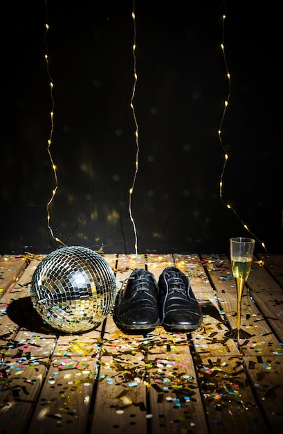 Gratis foto disco bal, laarzen voor mannen en een glas drank tussen confetti