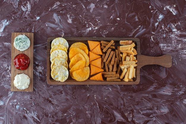 Gratis foto diverse chips op serveerplank met saus, op de marmeren tafel.