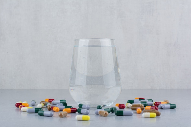 Diverse farmaceutische capsules en glas water.