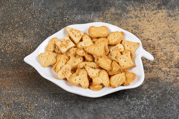 Diverse gevormde gezouten crackers op bladvormig bord.