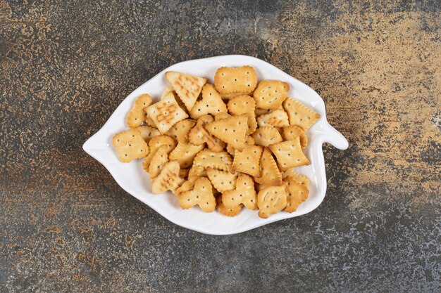 Diverse gevormde gezouten crackers op bladvormig bord.