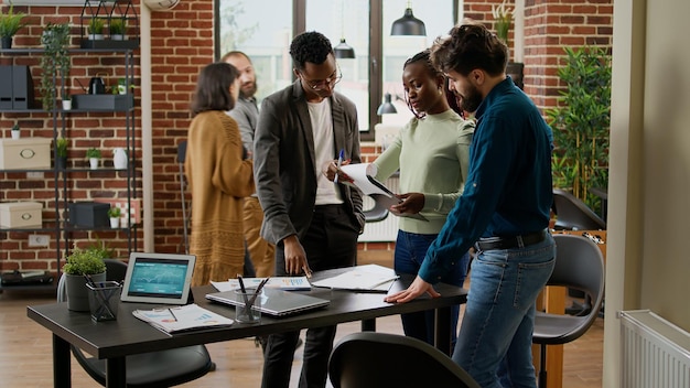 Diverse groep collega's die onderzoeksanalyse plannen in het bedrijfsbureau, werken aan een startup-partnerschap om een projectrapport te maken met diagramgegevens en statistieken. Met behulp van documenten en digitale tablet.